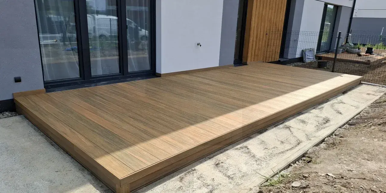 Nowy taras na słupach betonowych, wykonany z desek kompozytowych, stanowi idealne miejsce do wypoczynku.