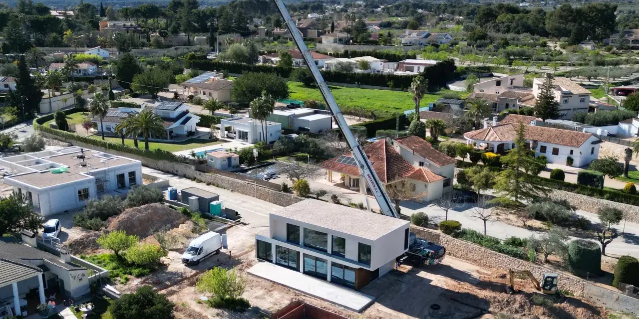 Construcción moderna en zona residencial, mostrando la diferencia entre urbano y urbanizable con grúa y excavadora.