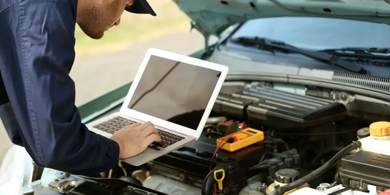Mechanik diagnozuje usterkę w Oplu p2279, używając laptopa i multimetru.