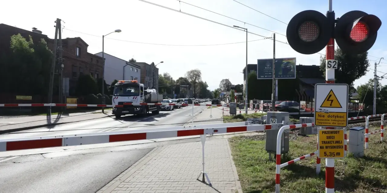 Przejazd kolejowy z zaporami i czerwonymi światłami. Samochód ciężarowy czeka na przejazd.