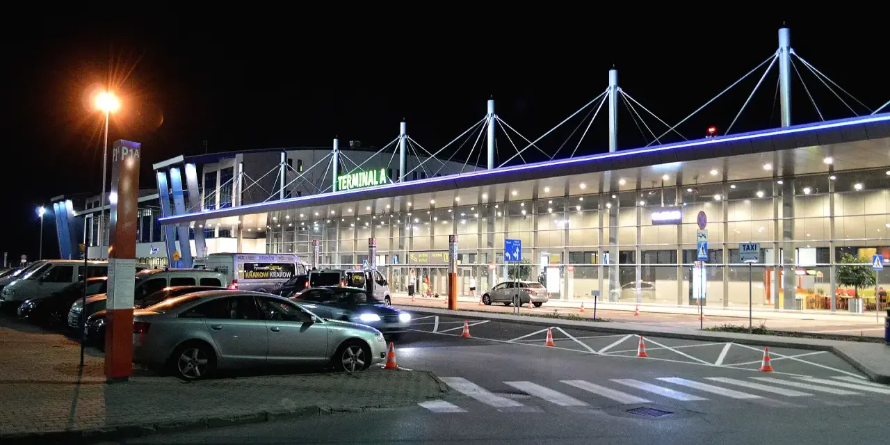 Nocne lotnisko Kraków-Balice, Terminal A. Samochody czekają na pasażerów, a światła tworzą niepowtarzalny klimat.