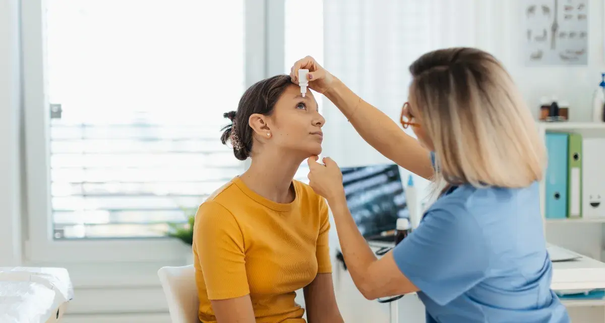 Medico applica cortisone collirio a una giovane paziente in ambulatorio.