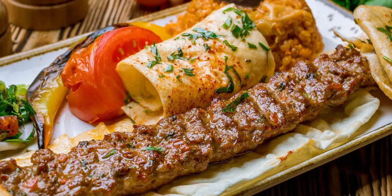 Kebab na talerzu z warzywami i plackiem.
