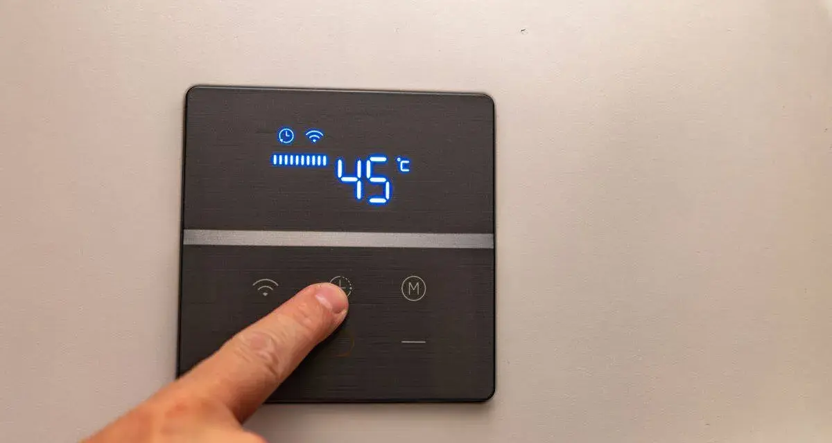 Dito, un dito preme il pulsante di un pannello digitale che mostra l'indicatore temperatura scaldabagno a 45°C, con icone Wi-Fi e di riscaldamento attive.