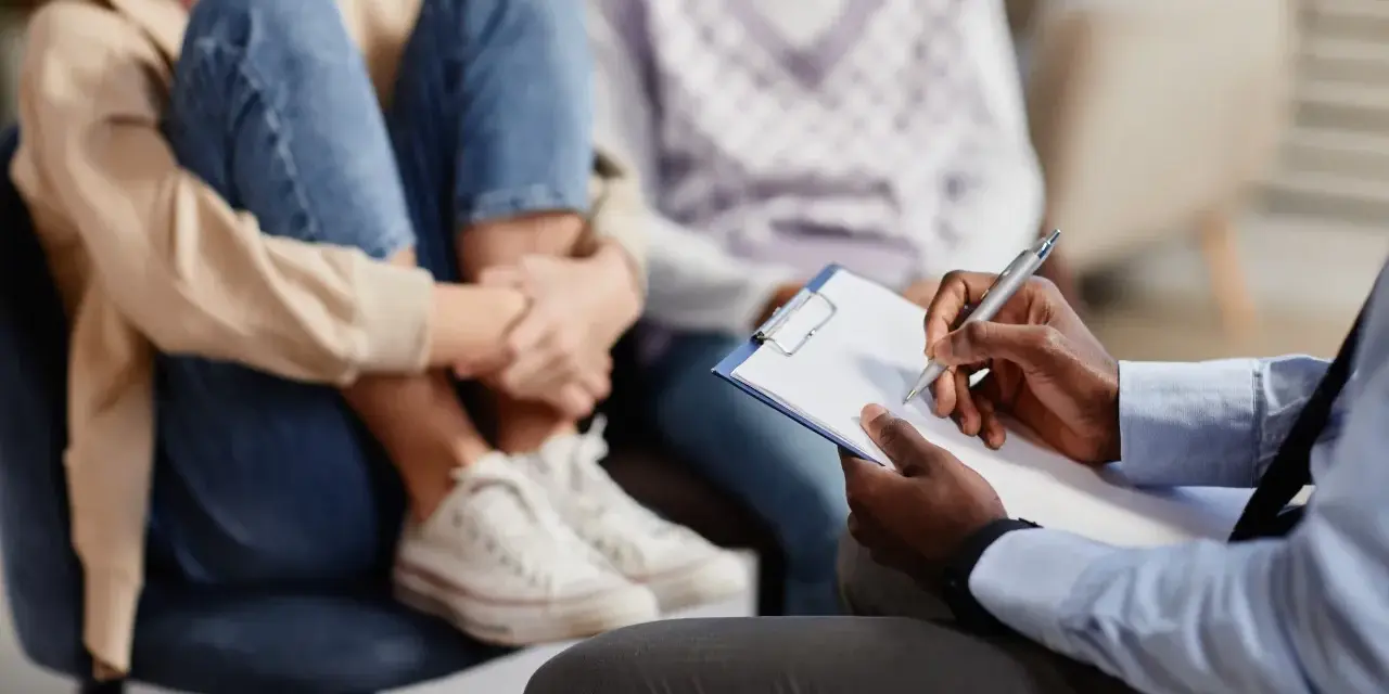 Un professionnel note des informations sur un jeune en difficulté, peut-être pour savoir comment faire une information préoccupante.