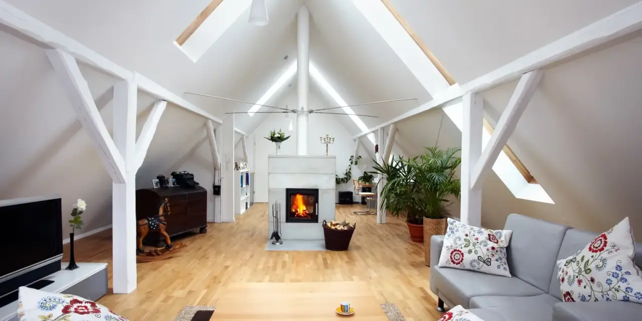Aménagement comble 30m2 : salon cosy avec cheminée, canapé gris, parquet clair et poutres apparentes.
