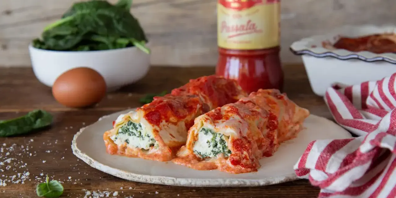 Cannelloni ricotta e spinaci fumanti, conditi con passata Mutti e formaggio filante, pronti per essere gustati.