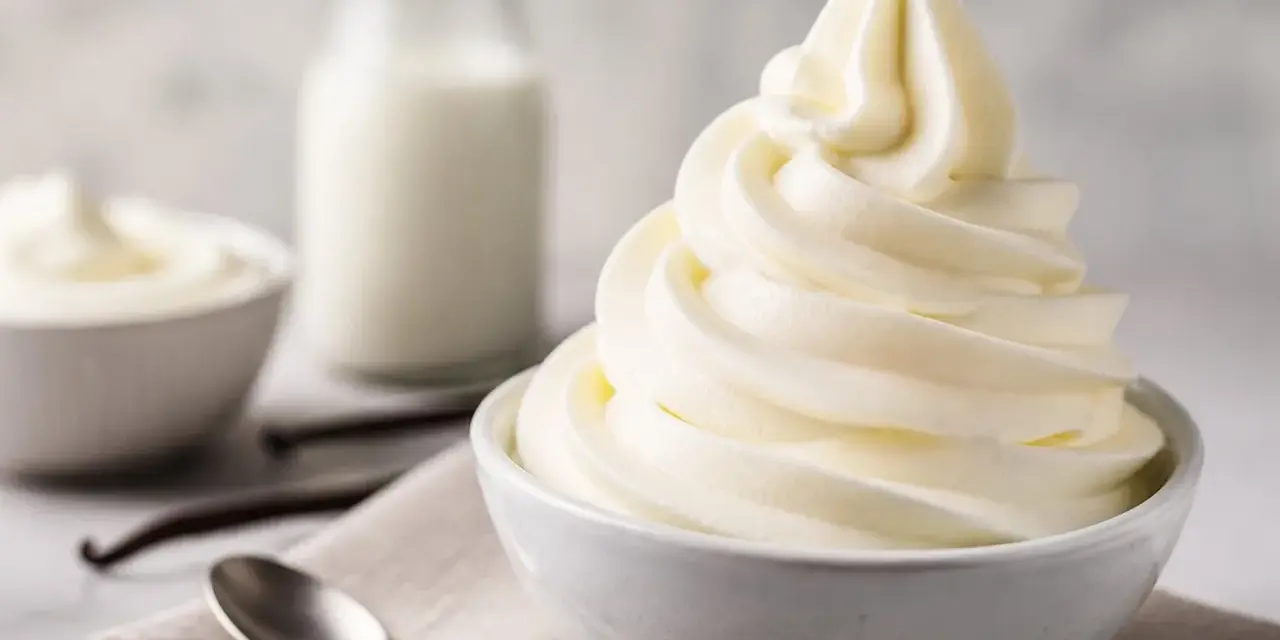 Cremiges Softeis in einer Schüssel, daneben Milch, Vanilleschoten und Löffel. Die Zutaten für das perfekte Softeis.