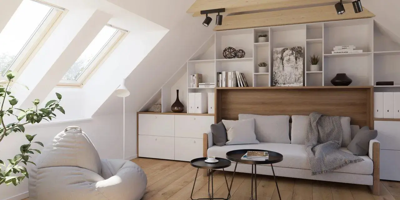 Accogliente salotto in mansarda con divano, pouf, libreria e lucernari che inondano lo spazio di luce.