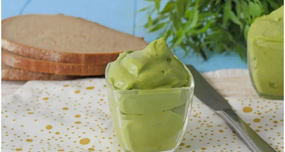 Deliziosa maionese di avocado in una ciotola di vetro, pronta per essere spalmata su fette di pane integrale.