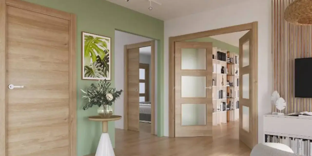 Un pasillo con paredes verde menta y puertas de roble. Un cuadro de hojas tropicales y un jarrón con flores adornan la pared.