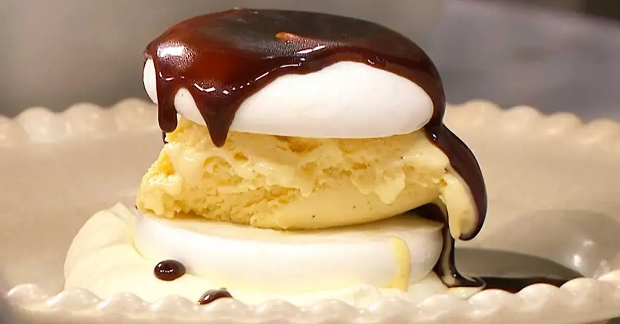 En läcker banana split med vaniljglass, maräng och chokladsås som rinner ner.