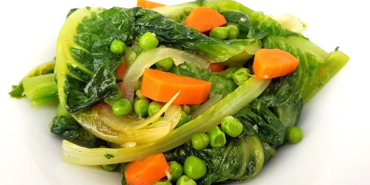 Un assortiment coloré de légumes verts feuillus, de pois et de carottes en dés, rappelant une jardinière de légumes fraîchement préparée.