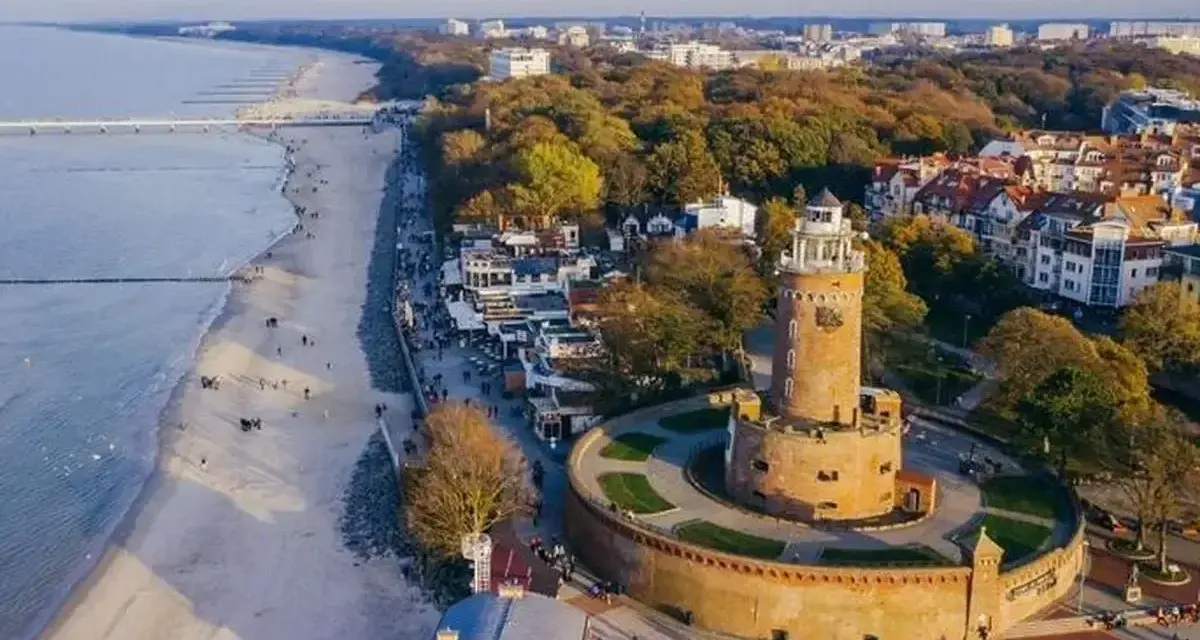 Widok z lotu ptaka na latarnię morską w Darłowie, plażę i nadmorskie miasteczko.