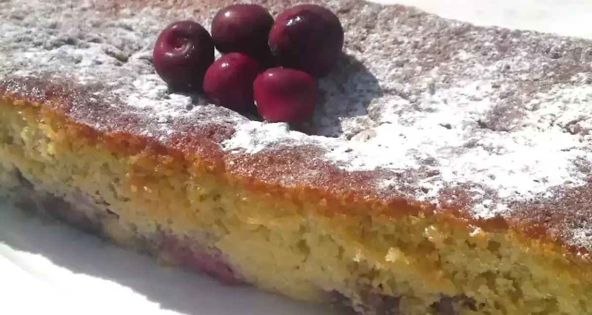 Bizcocho de cerezas casero, espolvoreado con azúcar glas y decorado con cerezas frescas.