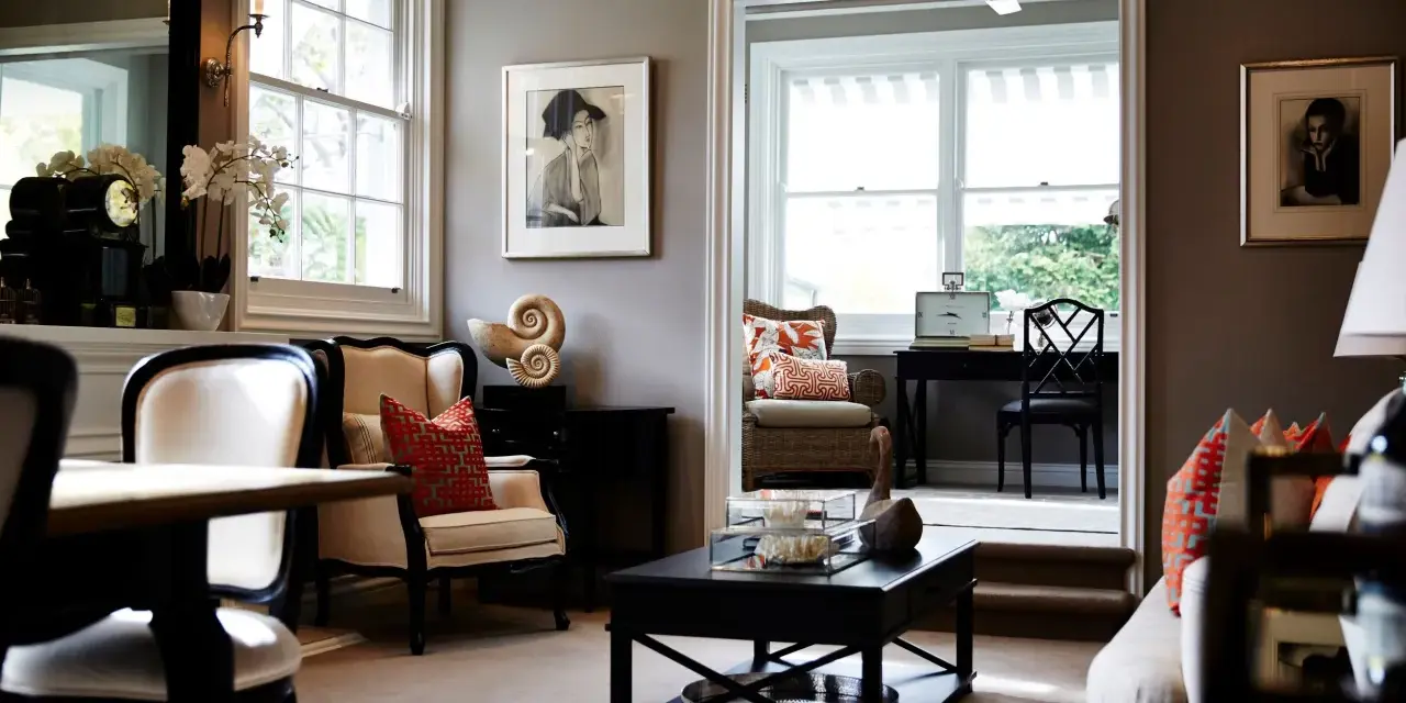Elegante salón con paredes color topo oscuro, muebles clásicos y obras de arte.