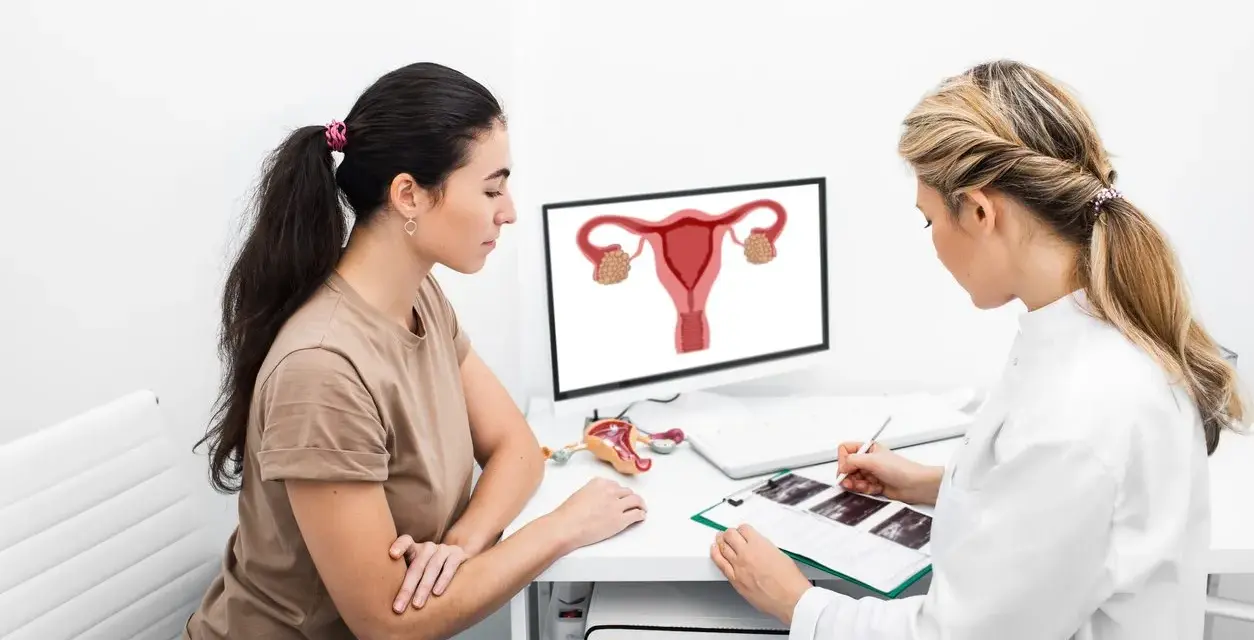 Lekarka wyjaśnia pacjentce, co to jest endometrium, pokazując schemat narządów rodnych na monitorze.