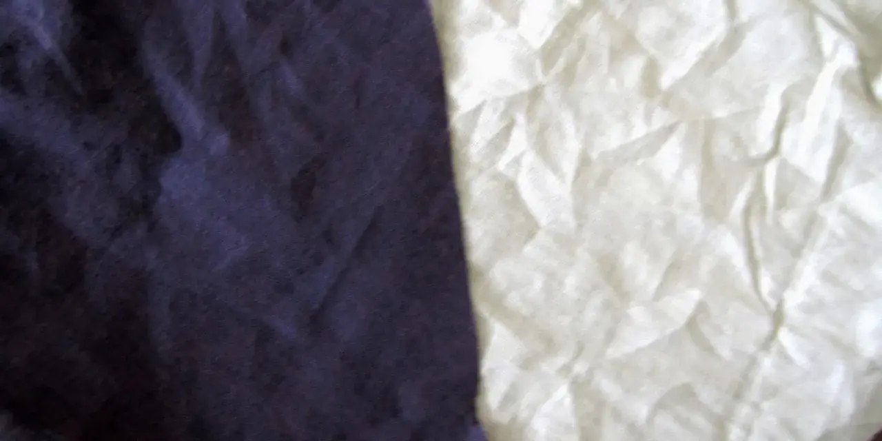 Dwa kawałki materiału, jeden granatowy, drugi biały, przypominają, że **cotton co to** za materiał – miękki i naturalny.