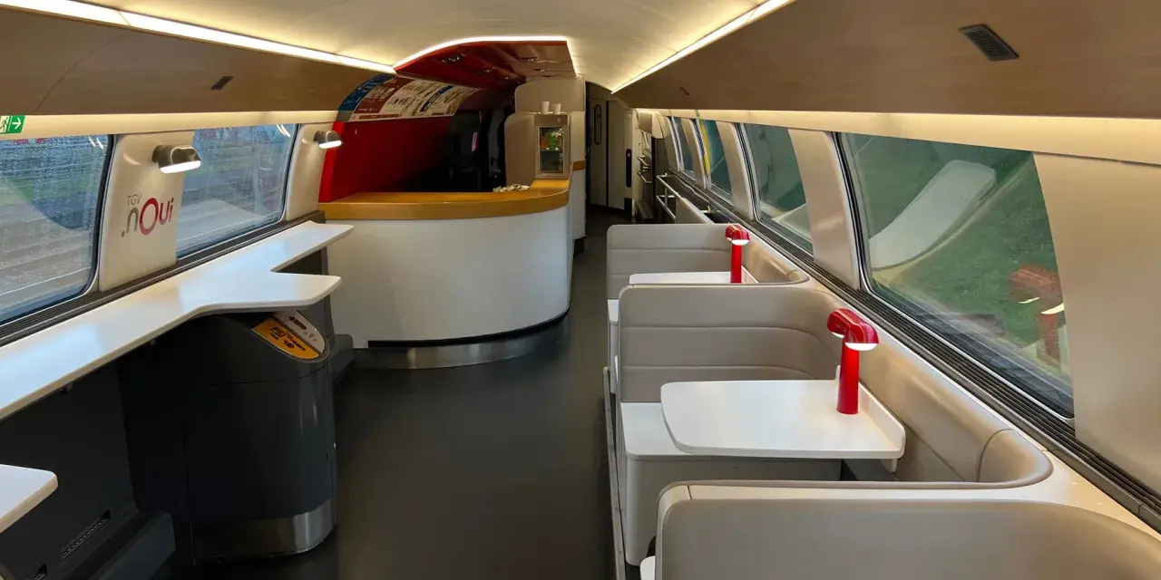 Interior of a TGV train carriage, ready for a journey from Amsterdam to Bordeaux. Booth seating and a bar area await passengers.