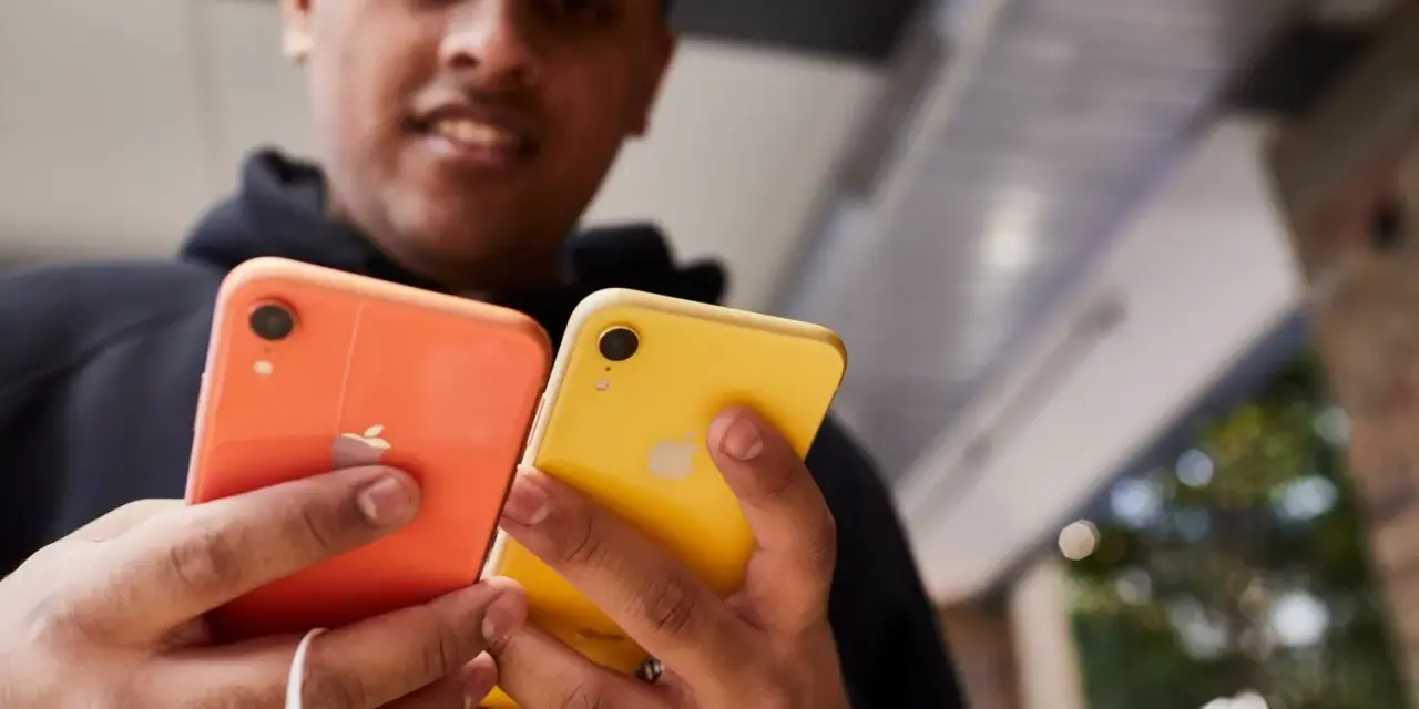 Mężczyzna trzyma dwa telefony: pomarańczowy i **iphone xr żółty**.