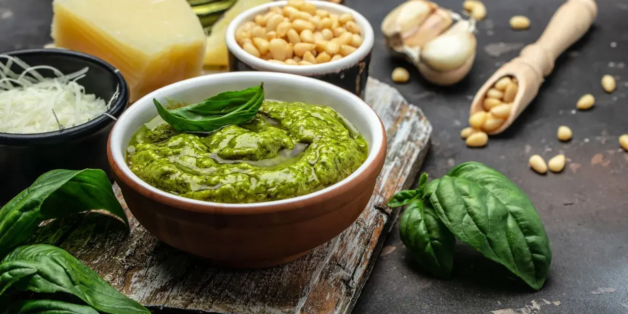 Un tazón de pesto genovés fresco con albahaca, piñones, ajo, queso parmesano y aceite de oliva.