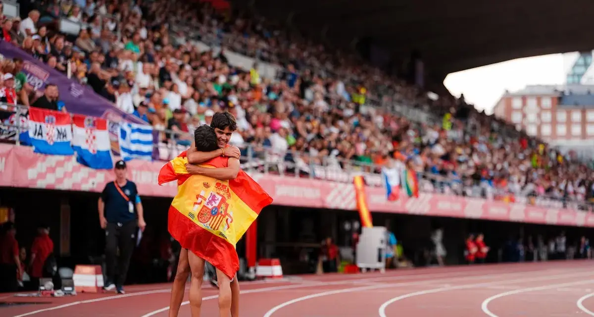 Dos atletas se abrazan con la bandera de España en el campeonato Europa sub 20 atletismo.