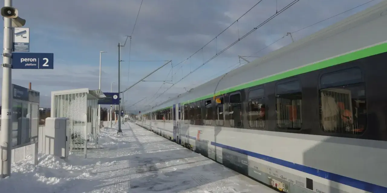 Zimowy peron 2, śnieg i pociąg do Krakowa czekają na pasażerów.