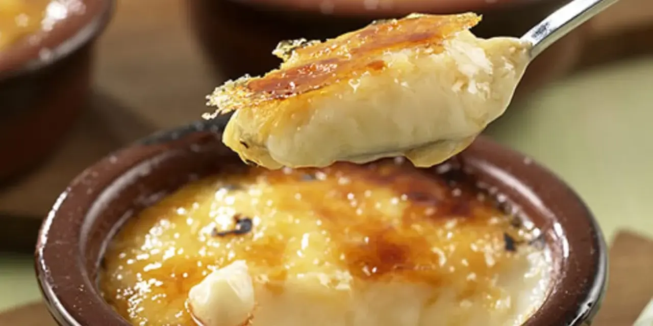 Cremige Crema Catalana Eis wird von einem Löffel aufgetischt, die karamellisierte Kruste bricht.