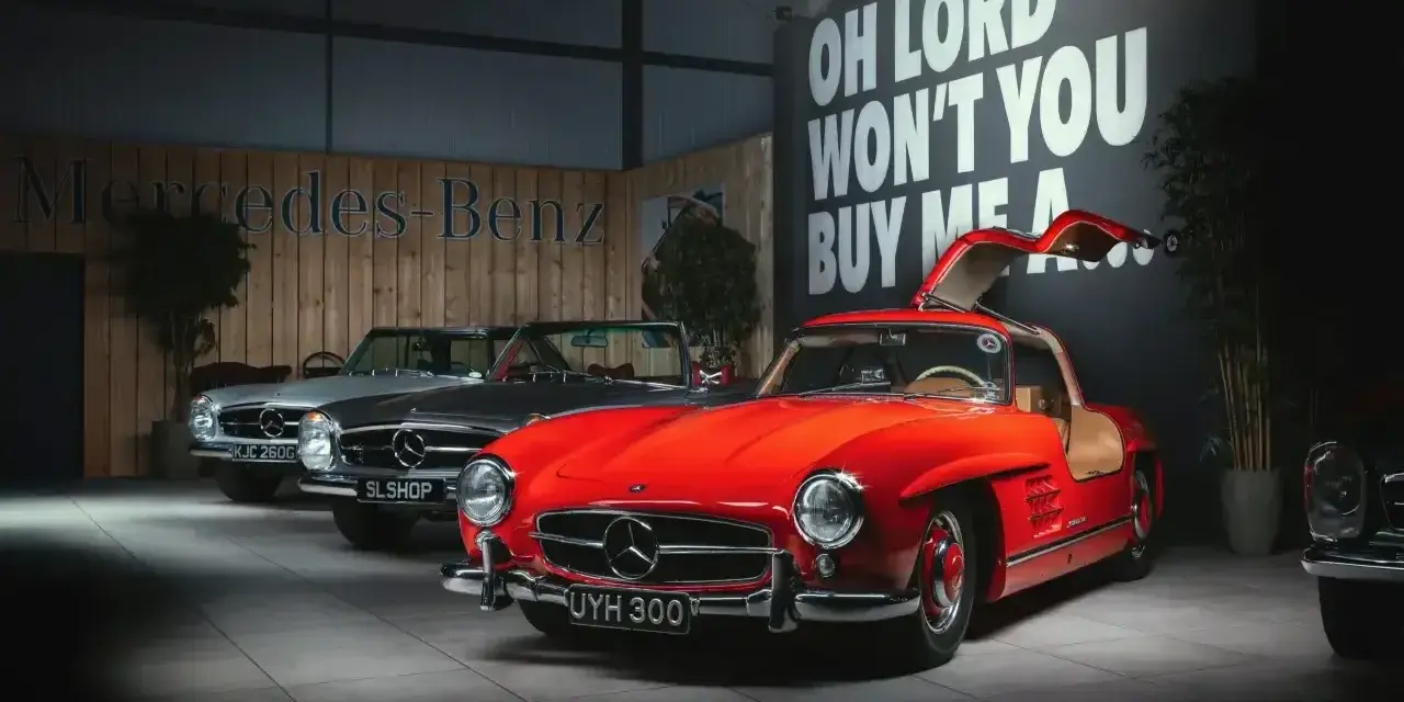Czerwony Mercedes 300 z drzwiami skrzydłowymi, obok srebrny i szary model.