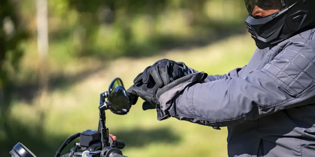 Motociclista con casco integrale obbligatorio e guanti neri, pronto per un viaggio su strada.