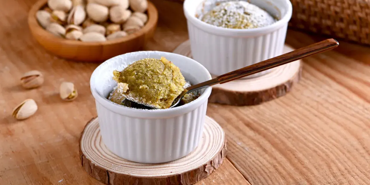 Un delicioso coulant de pistacho, recién horneado y espolvoreado con azúcar glas. ¡Una delicia para los sentidos!