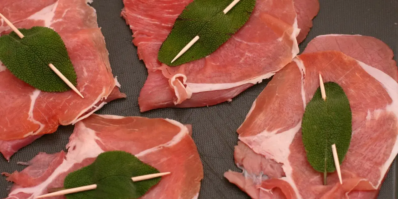 Fette di vitello pronte per la saltimbocca alla romana ricetta originale, con prosciutto crudo e foglie di salvia fissate con stuzzicadenti.