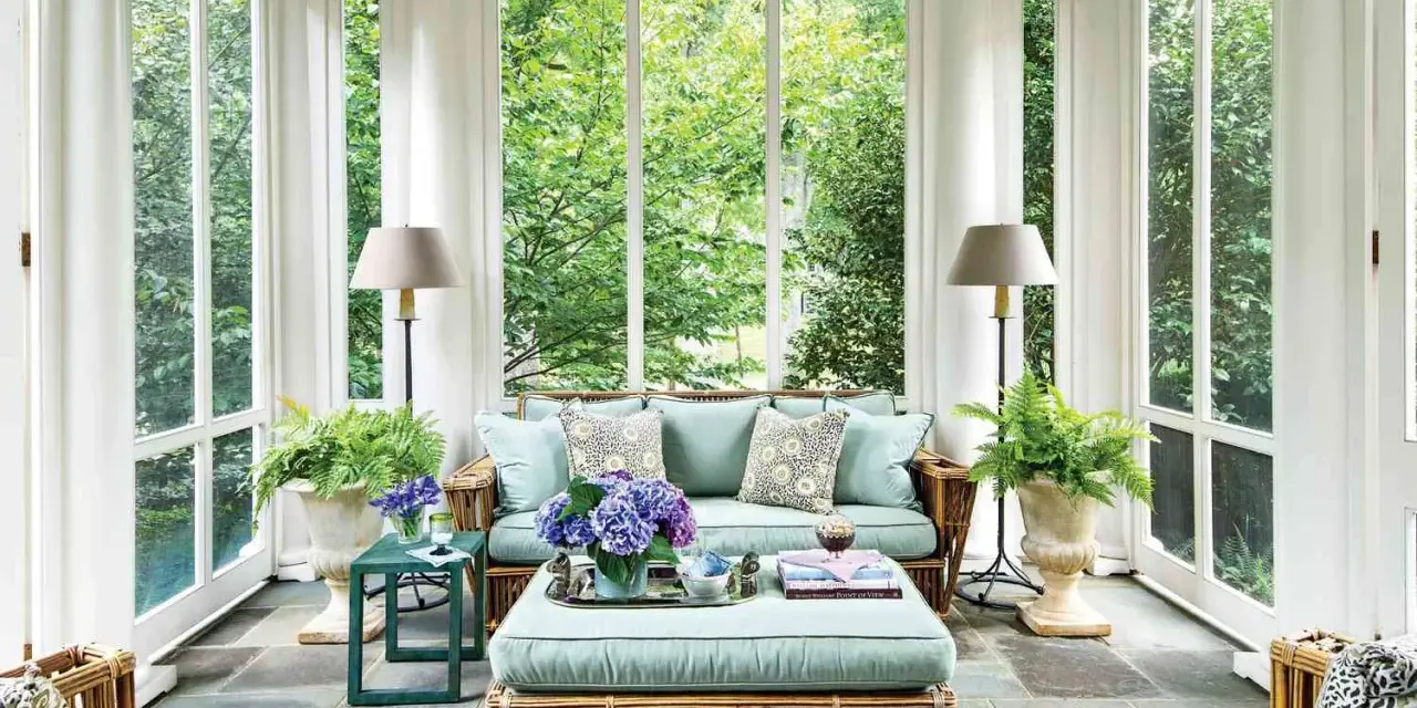 A serene screen porch with rattan furniture, plush cushions, and lush greenery. The natural screen porch materials create a cozy, inviting atmosphere.