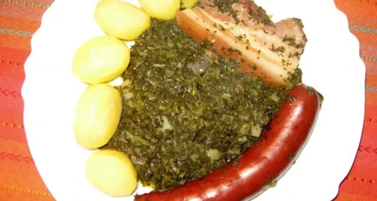 Gedünsteter Grünkohl mit Salzkartoffeln, Kassler und einer herzhaften Lungenwurst, die zum Kochen oder Braten bereit ist.