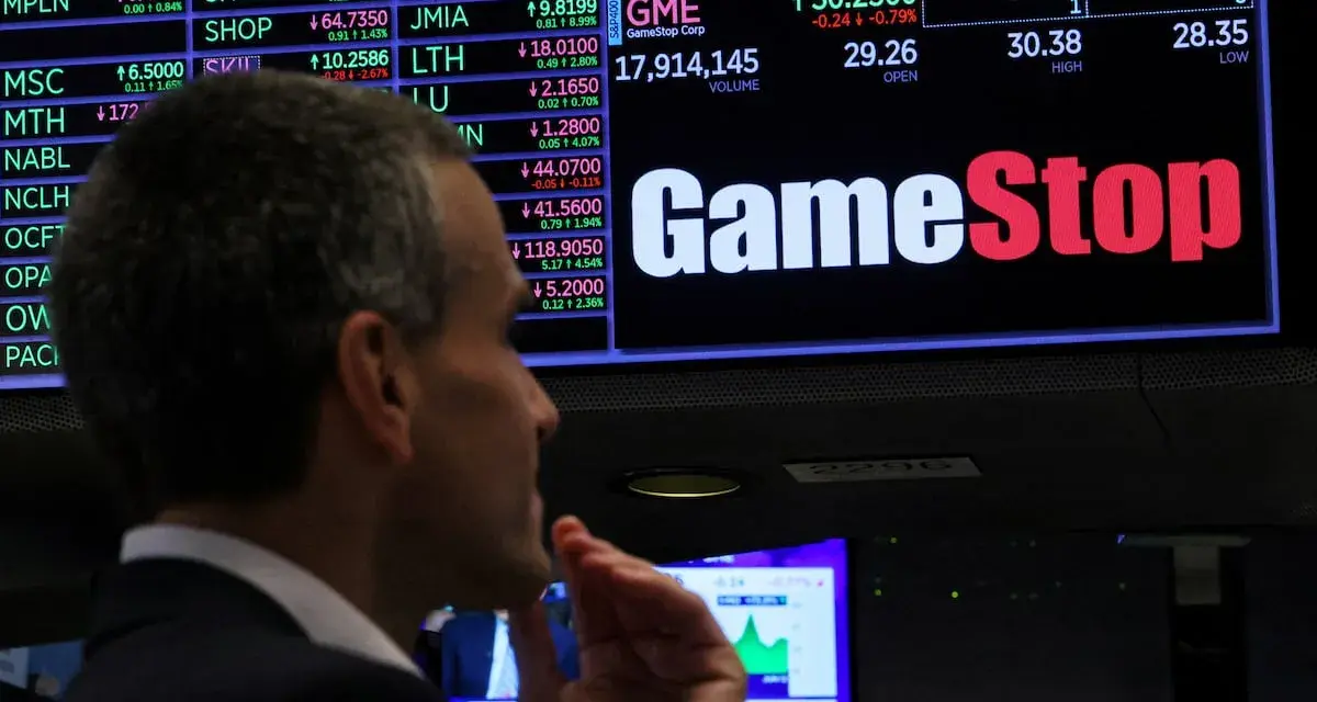 Un hombre observa la pantalla de cotizaciones de GameStop, analizando la previsión de fondos y el comportamiento del mercado.