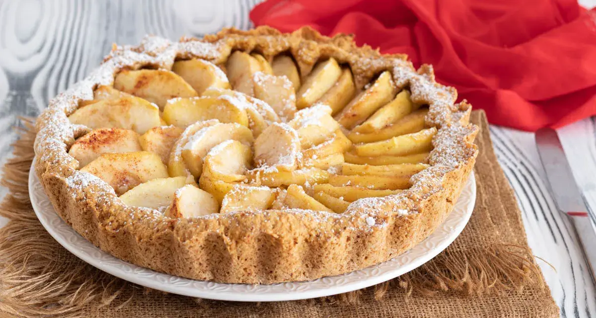 Una deliziosa crostata di mele, con mele a fette disposte a raggiera e spolverata di zucchero a velo.