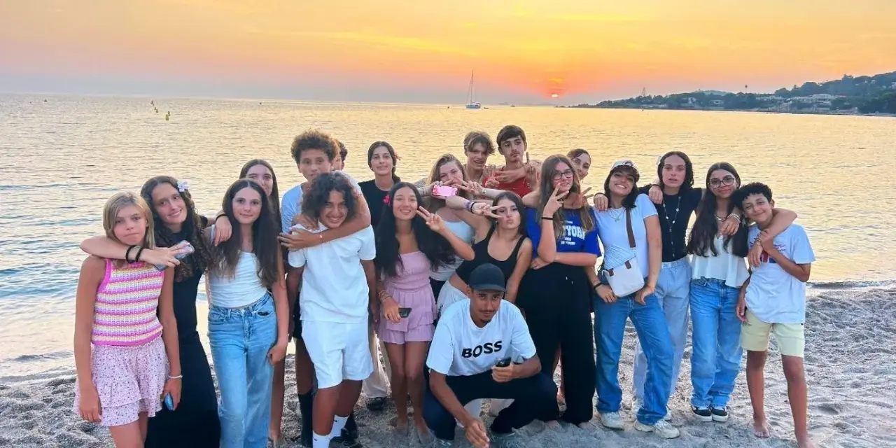 Groupe d'adolescents souriants sur une plage corse au coucher du soleil.