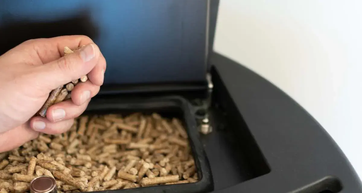 Mano cargando pellets en una estufa de pellets. Preparando la instalación de la estufa de pellets para un invierno cálido.
