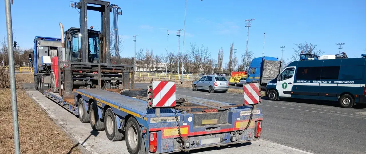 Ciężarówka z naczepą przewozi wózek widłowy. To przykład pojazdu nienormatywnego, który wymaga specjalnych zezwoleń.
