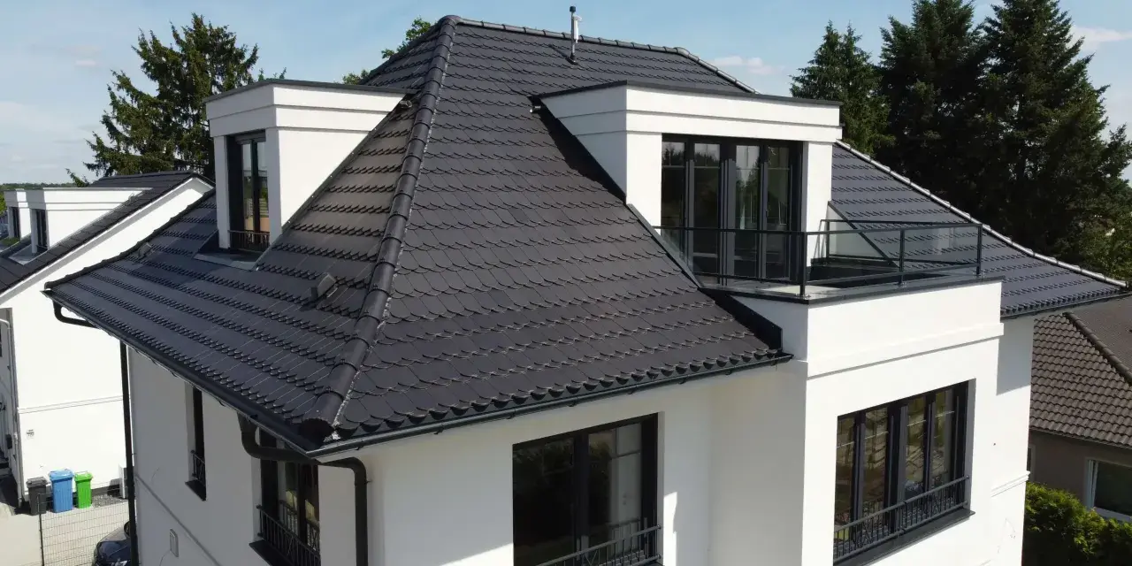 Modernes Haus mit dunkler Dachbeschichtung. Mögliche Nachteile der Dachbeschichtung: Hitzestau im Sommer, höhere Kosten bei Reparaturen.