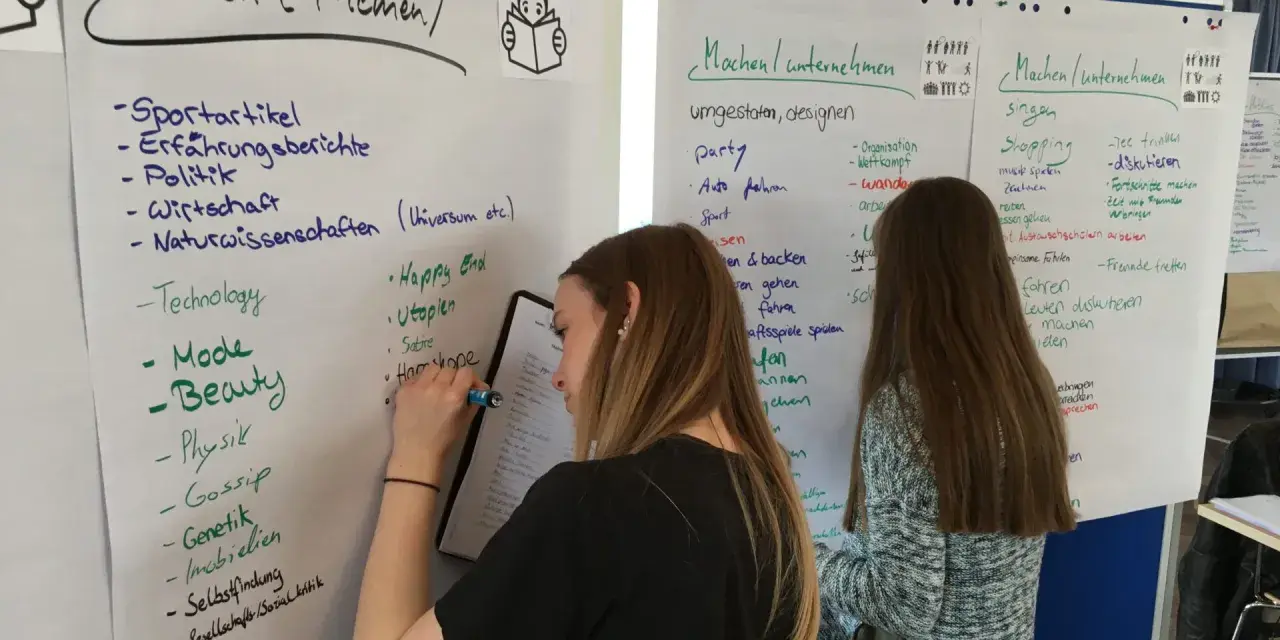 Zwei junge Frauen bei einem Praktikum zur Berufsorientierung, die Ideen auf Whiteboards sammeln.