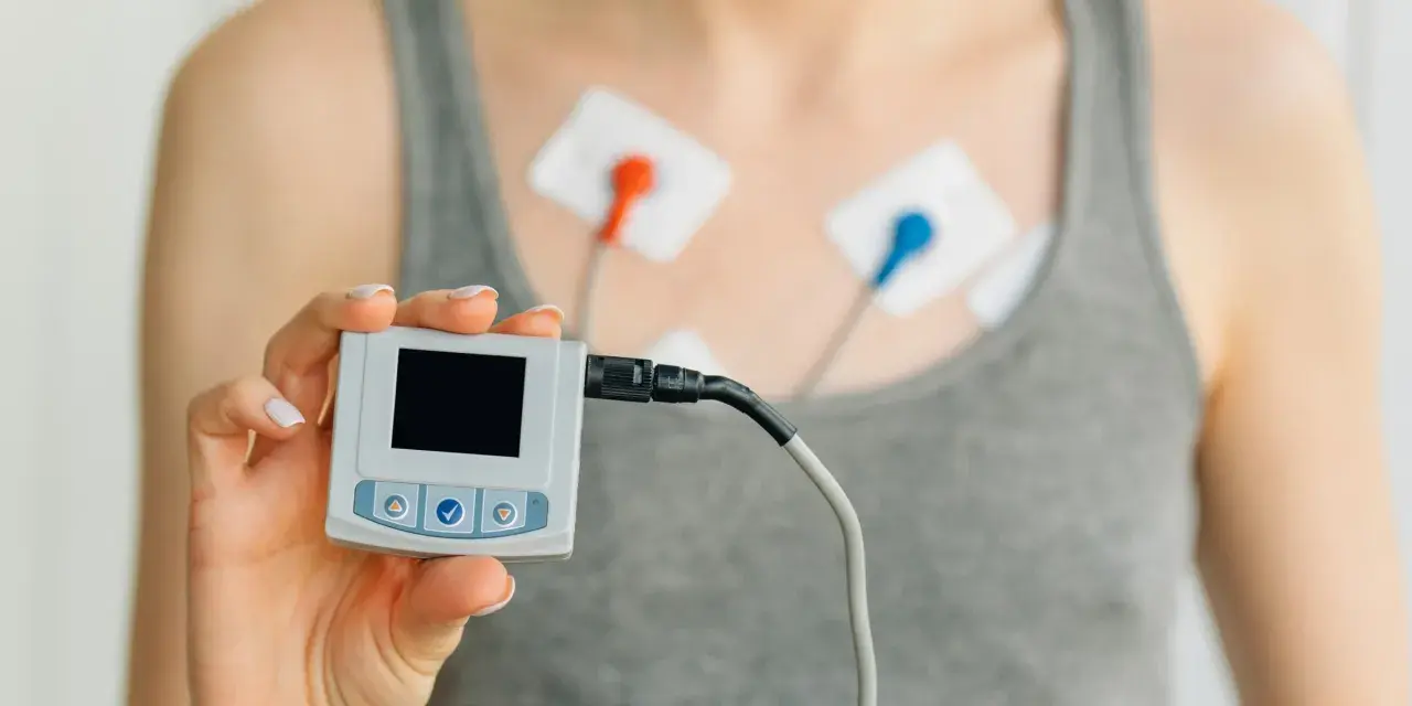 Holter co to? Urządzenie do monitorowania pracy serca z elektrodami na klatce piersiowej i małym rejestratorem w dłoni.