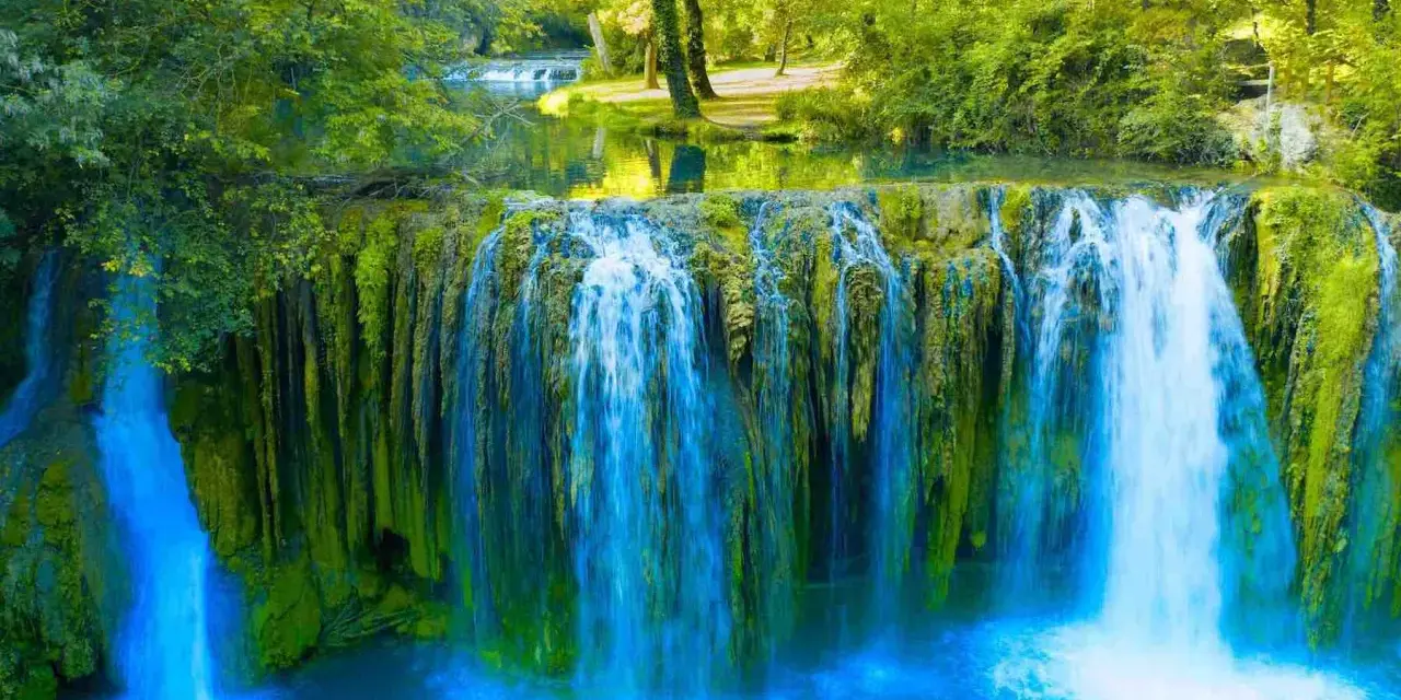 Cascata rigogliosa in Toscana, ideale per escursioni nella natura. Acqua cristallina e vegetazione lussureggiante creano uno scenario incantevole.