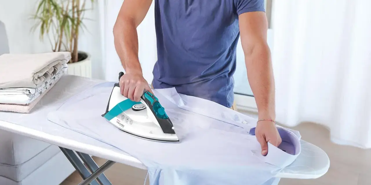 Uomo stira camicia, ma non esce vapore dal ferro da stiro con caldaia. La stiratura è difficile.