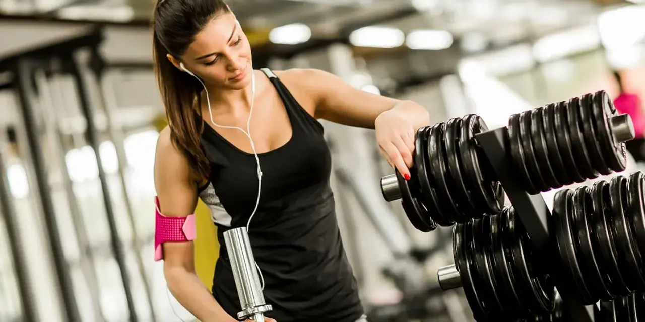 Kvinna väljer vikter på gymmet, bra gym tips för din träning.