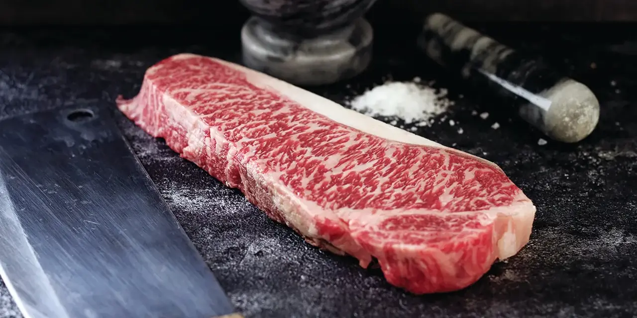 Wyjątkowy stek z krowy wagyu, gotowy do przygotowania. Obok nóż i moździerz z solą.