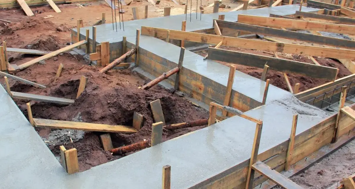 Budowa fundamentów: świeży beton i drewniane szalunki pokazują, jak połączyć stary fundament z nowym.