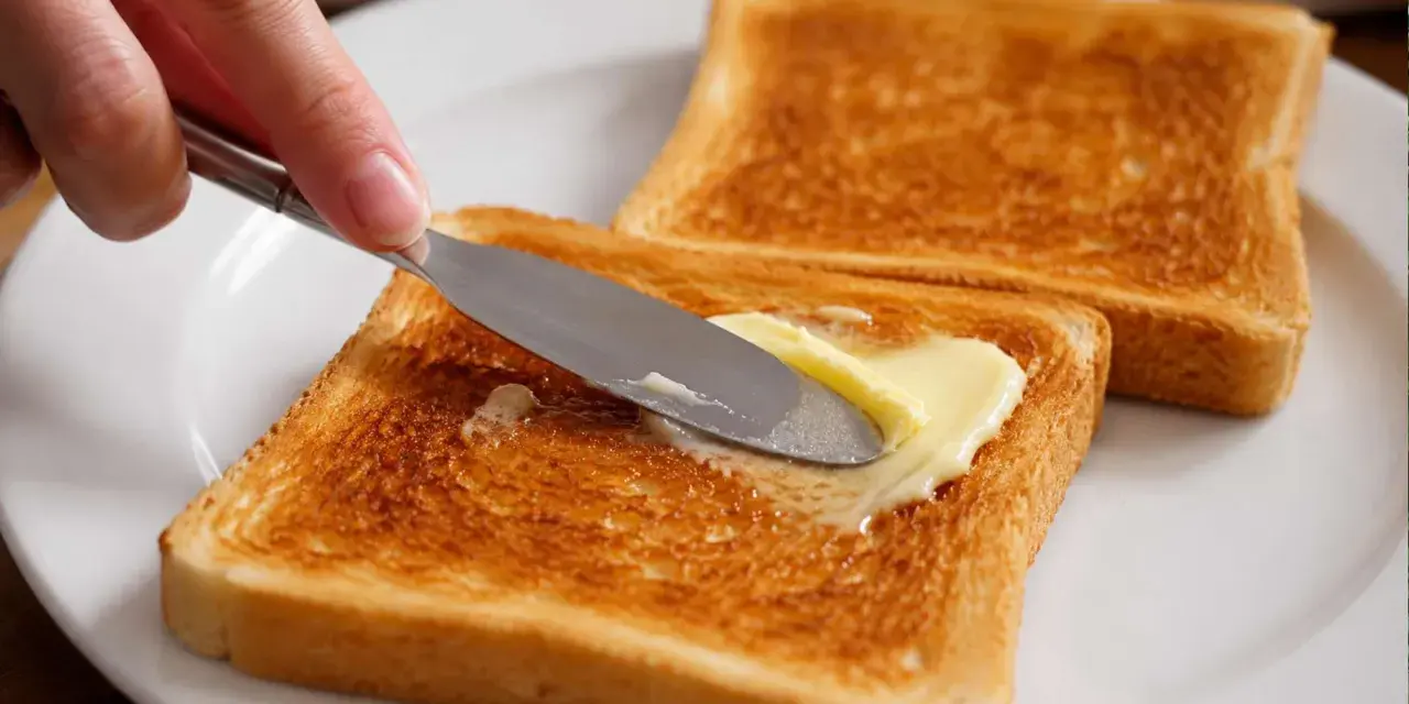 Goldbraunes Brot im Ofen getoastet, wird nun mit Butter bestrichen. Ein Genuss!