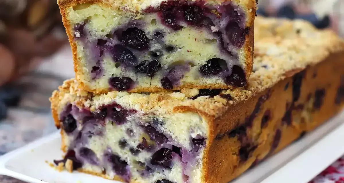 Saftiger Heidelbeerkuchen mit Streuseln, ein Stück gestapelt auf dem ganzen Kuchen. Köstlich!