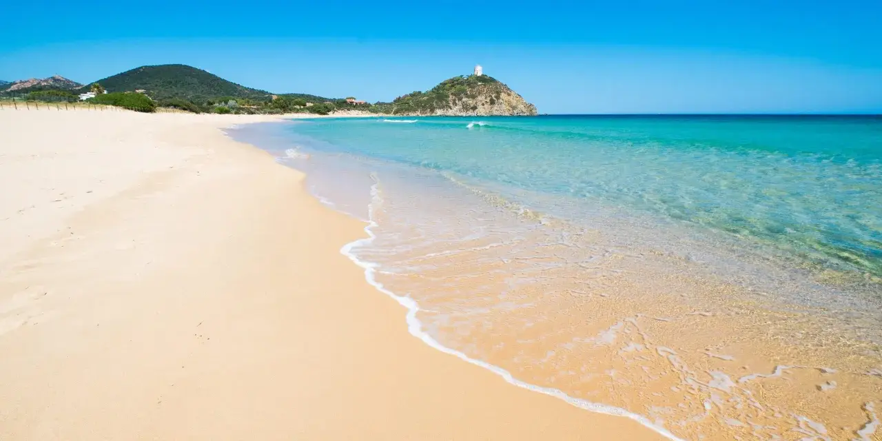 Piękne plaże Cagliari z turkusową wodą i piaszczystym brzegiem. W oddali widać wzgórze z wieżą.